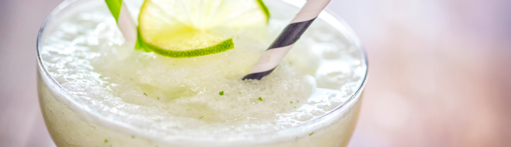 Frozen margarita cocktails with paper straws and lime garnish