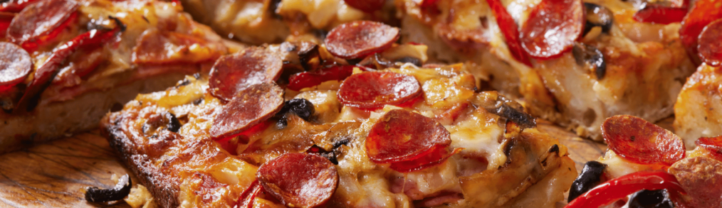 Close up of Detroit style pizza with pepperoni and black olive toppings.