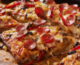 Close up of Detroit style pizza with pepperoni and black olive toppings.