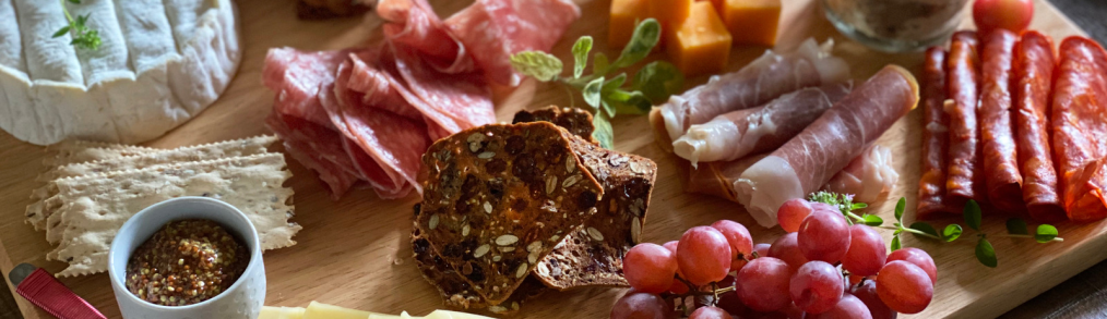 Charcuterie board of cheeses, meats, and fruit on wooden board