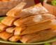 Stack of 10 tamales piled in pyramid on green plate - holiday food traditions