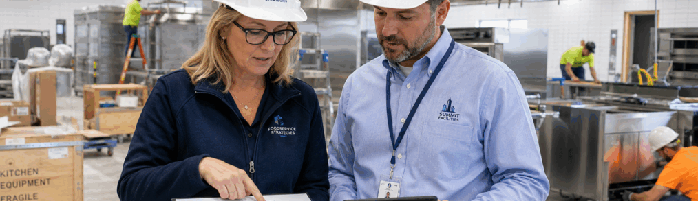 Consultant and facilities lead reviewing a phased schedule during a large scale kitchen installation