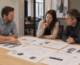 Operator and commercial kitchen equipment dealer team comparing equipment spec sheets and kitchen floor plans across a conference table