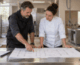 Facilities manager and chef reviewing a commercial kitchen floor plan at a prep table during a kitchen renovation